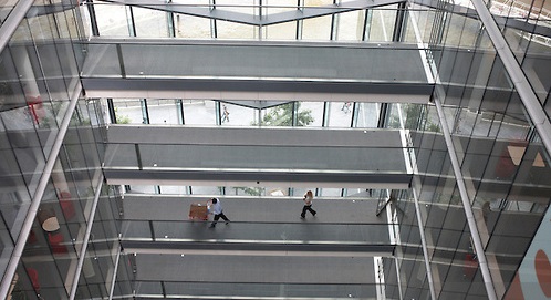Employees of auditing company Ernst & Young stride along lower middling walkways at the company's London headquarters